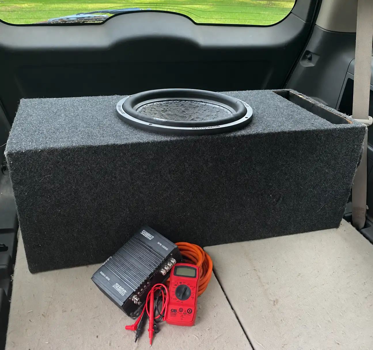 Subwoofer enclosure and amplifier installed in the rear cargo area of a vehicle